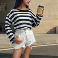 Woman wearing a striped cropped long-sleeved sweater in coloured cotton, showcasing the front and back wearable design.