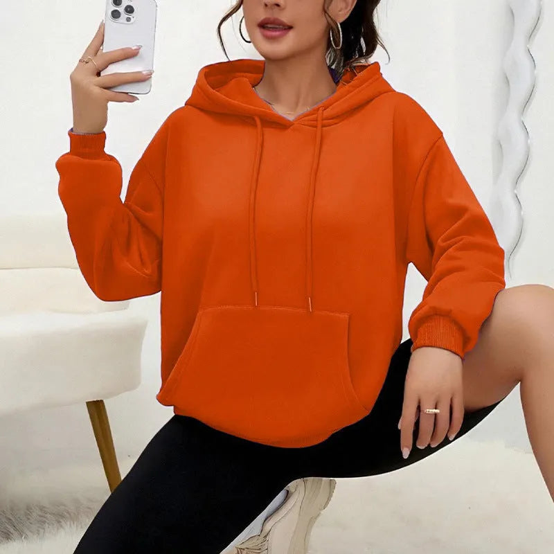 Woman wearing a loose grey drawstring hoodie with front kangaroo pocket, long sleeves.