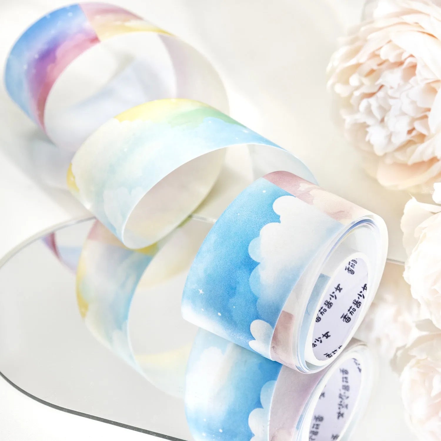 Roll of Japanese paper decorative tape with sky theme patterns including clouds, sun, moon, and nebula.