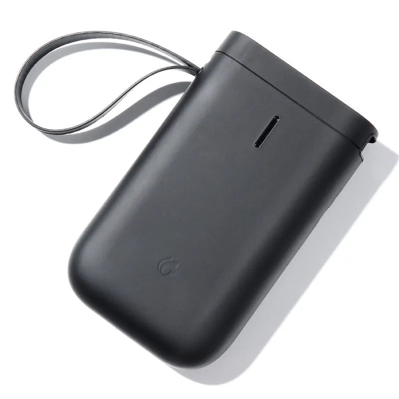 D11 Bluetooth label printer in black colour on a desk next to a smartphone showing the label design app.