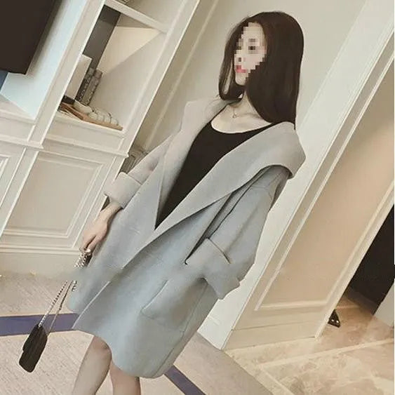 A plus-size woman wearing a loose grey cotton coat with lace details and long sleeves.