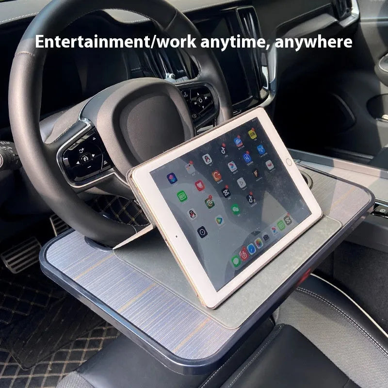 Black foldable car steering wheel laptop stand with integrated cup holder on a car seat.