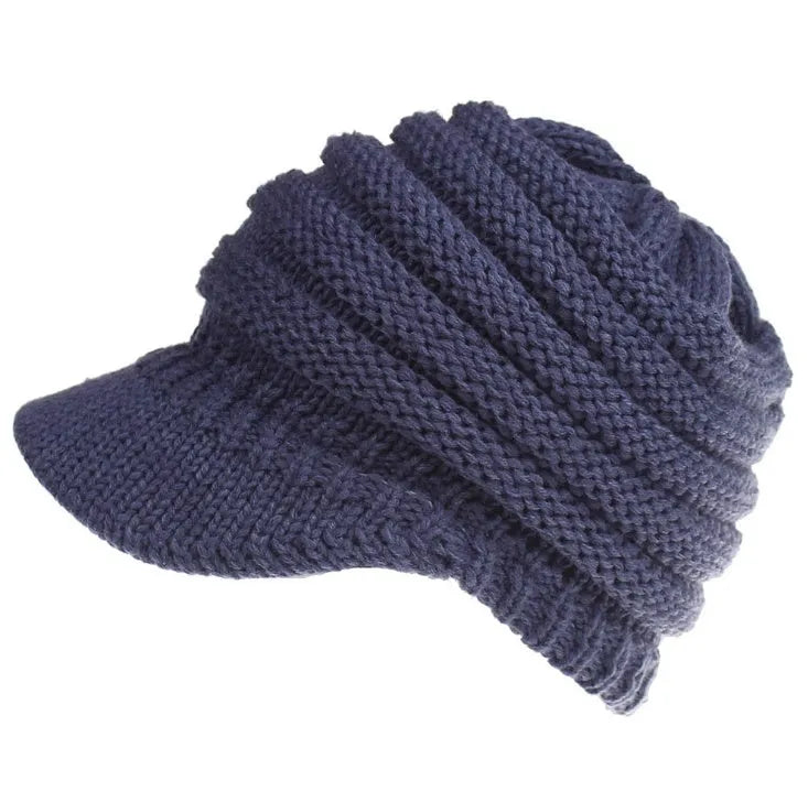 Woman wearing a thick knitted beanie with a ponytail threaded through the hole in the crown.