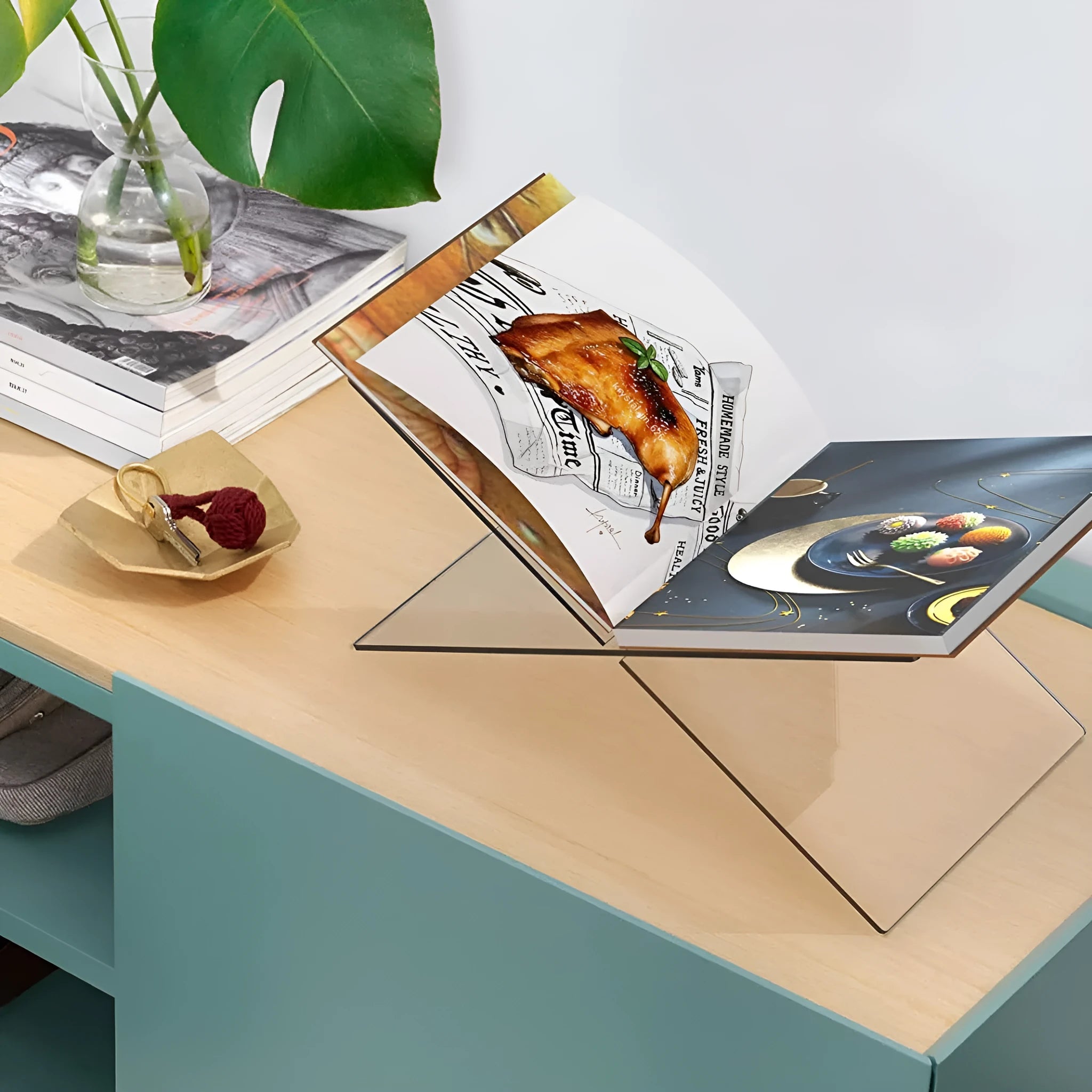 Transparent X-shaped acrylic book reading rack displaying books on desktop