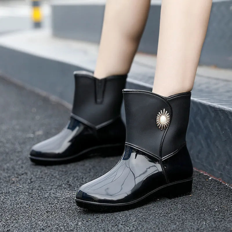 Women's purple PVC middle tube rain boots with a non-slip sole on a wet surface.