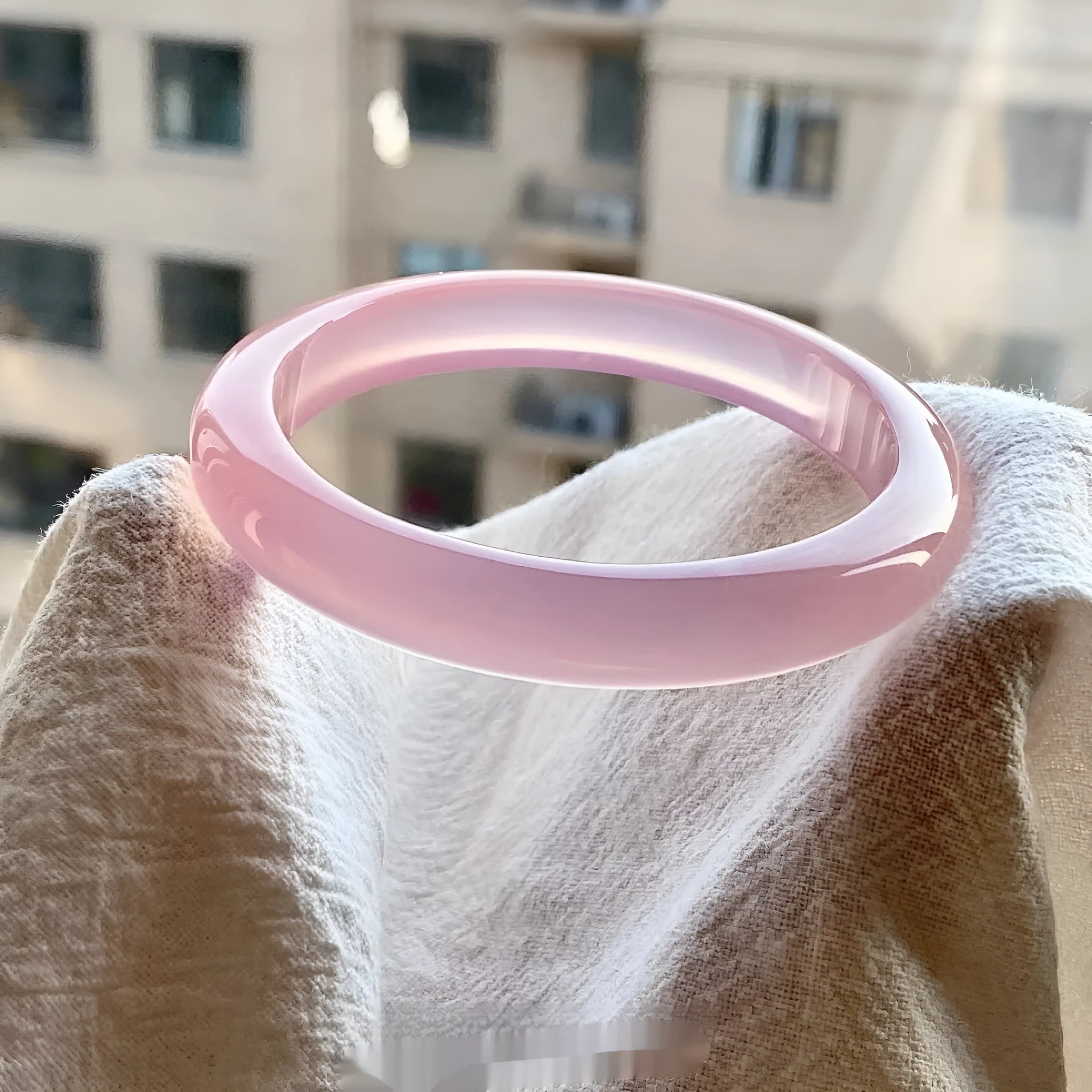 A natural agate wide tyre bracelet showing one of six colour options, such as pink or blue agate, on a wrist.