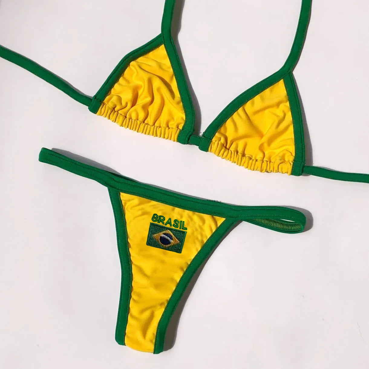 Women's yellow polyester bikini set with T-back bra and shorts-length bottoms laid flat.