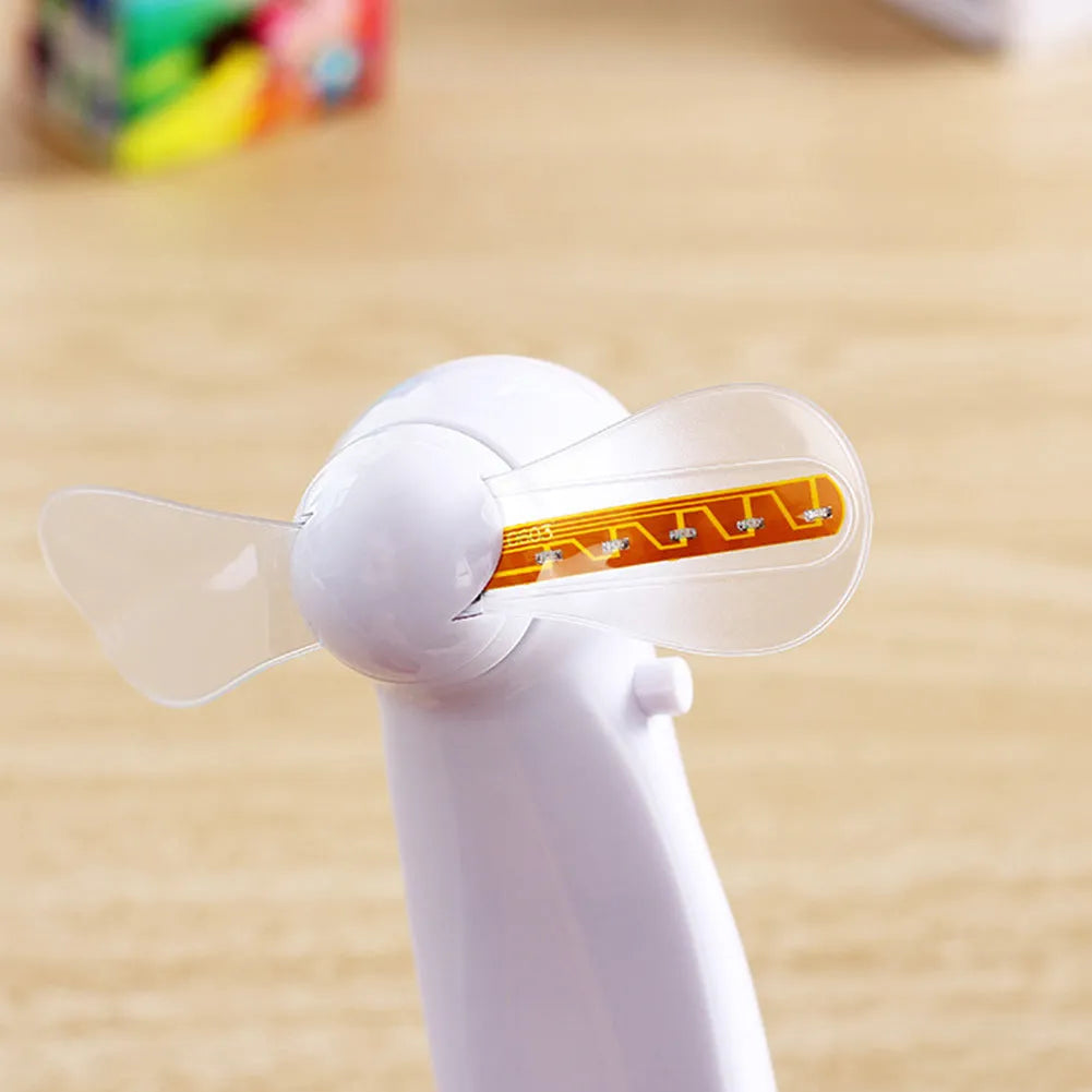 White handheld mini fan showing blue and red LED 'I Love You' pattern, held in hand.