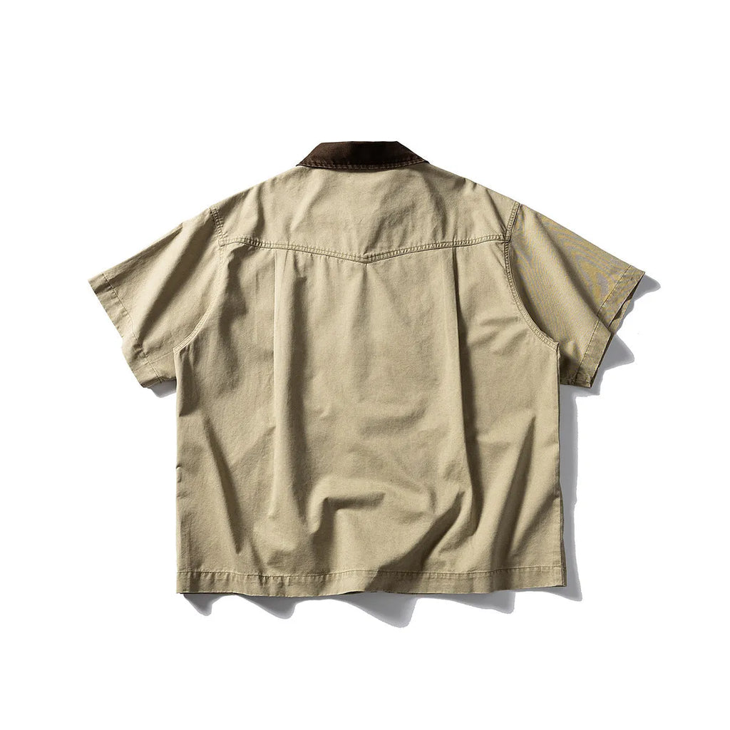 Loose grey short sleeve overalls shirt with cardigan front on a hanger.
