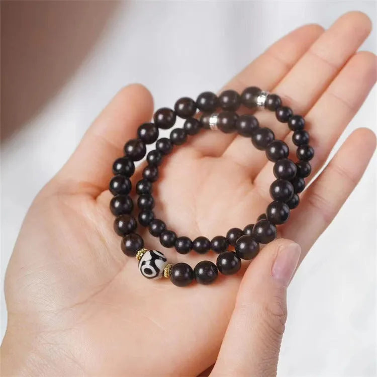 Ebony beaded bracelet with two-circle Tibetan-inspired design on wrist