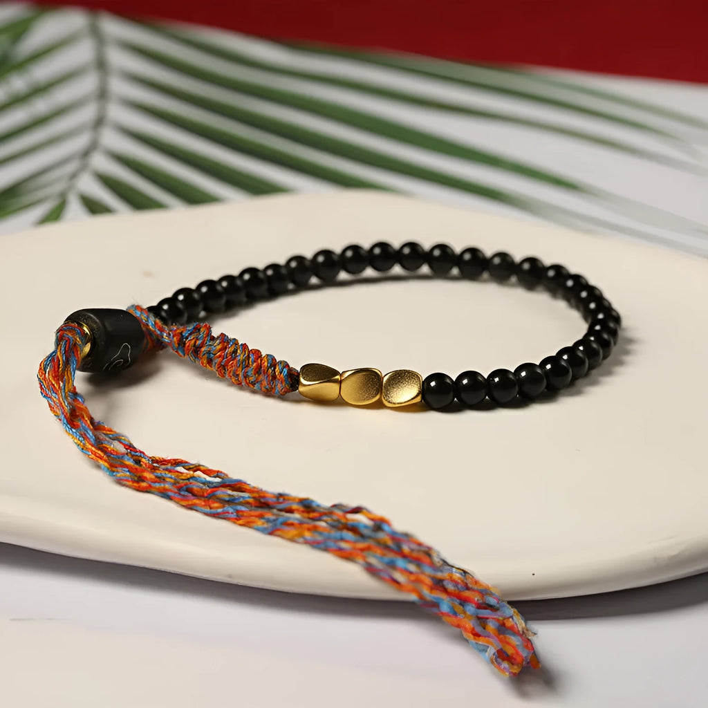 Hand-woven obsidian bracelet with dark beads showing woven texture and adjustable 15.5-16cm length