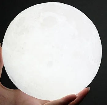3D printed moon lamp glowing on a wooden stand with touch ring at base