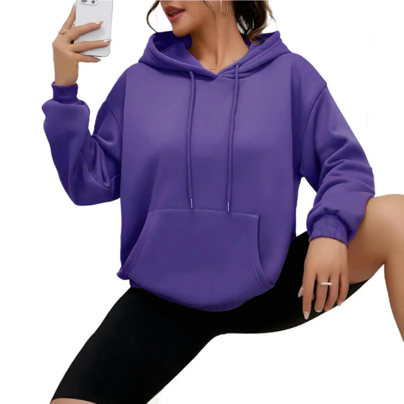 Woman wearing a loose grey drawstring hoodie with front kangaroo pocket, long sleeves.