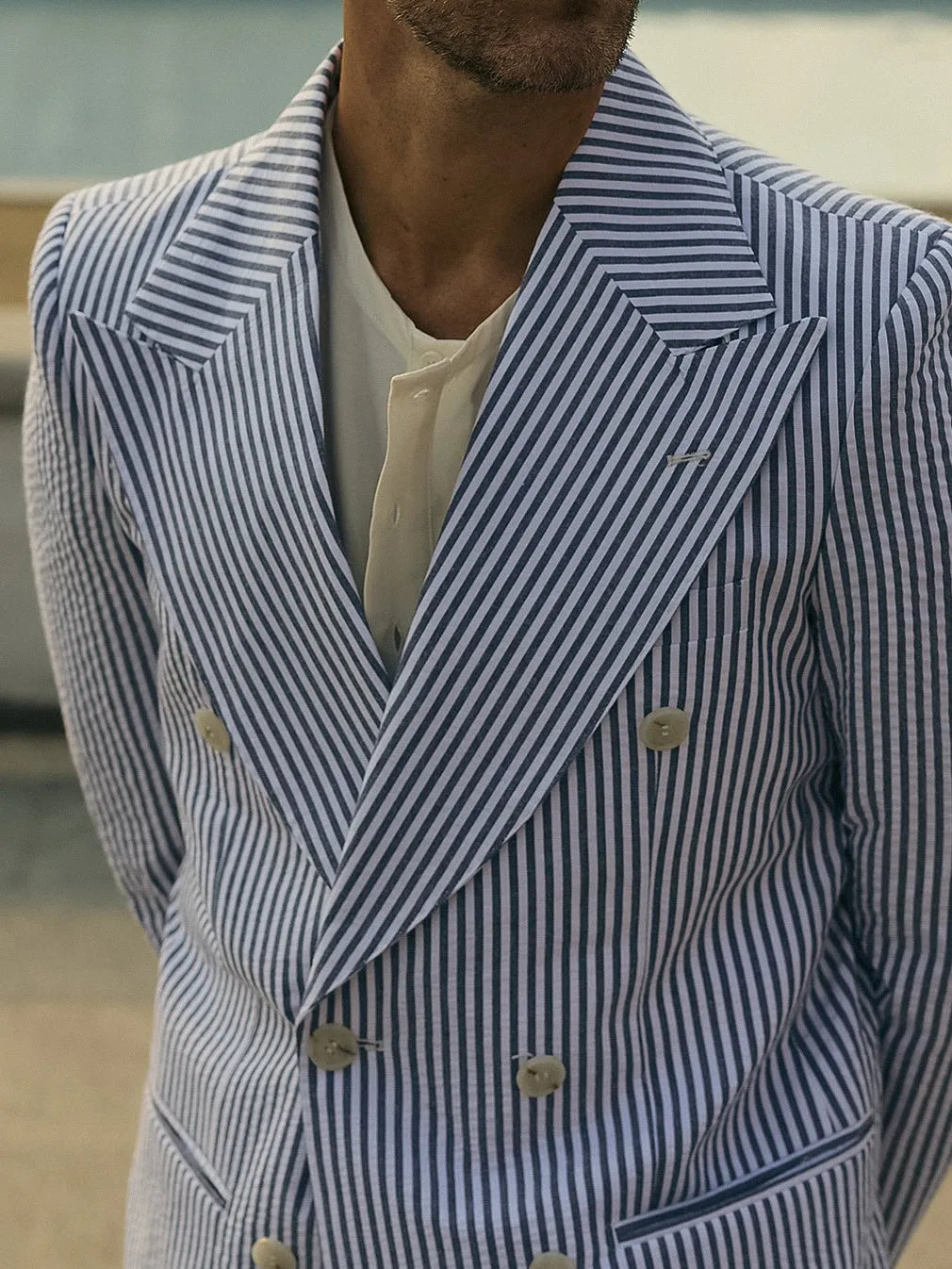 Blue and white striped polyester blazer and trousers suit set laid flat.
