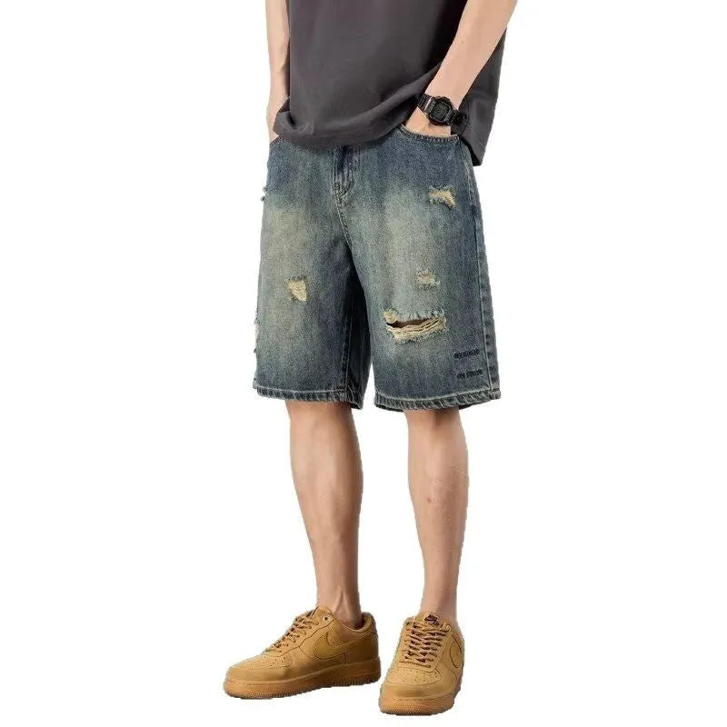 Man wearing blue retro loose-hole denim shorts with a straight leg cut on a casual background.