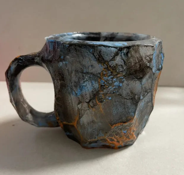 Purple and blue resin coffee mug with crystal texture and handle on wooden table
