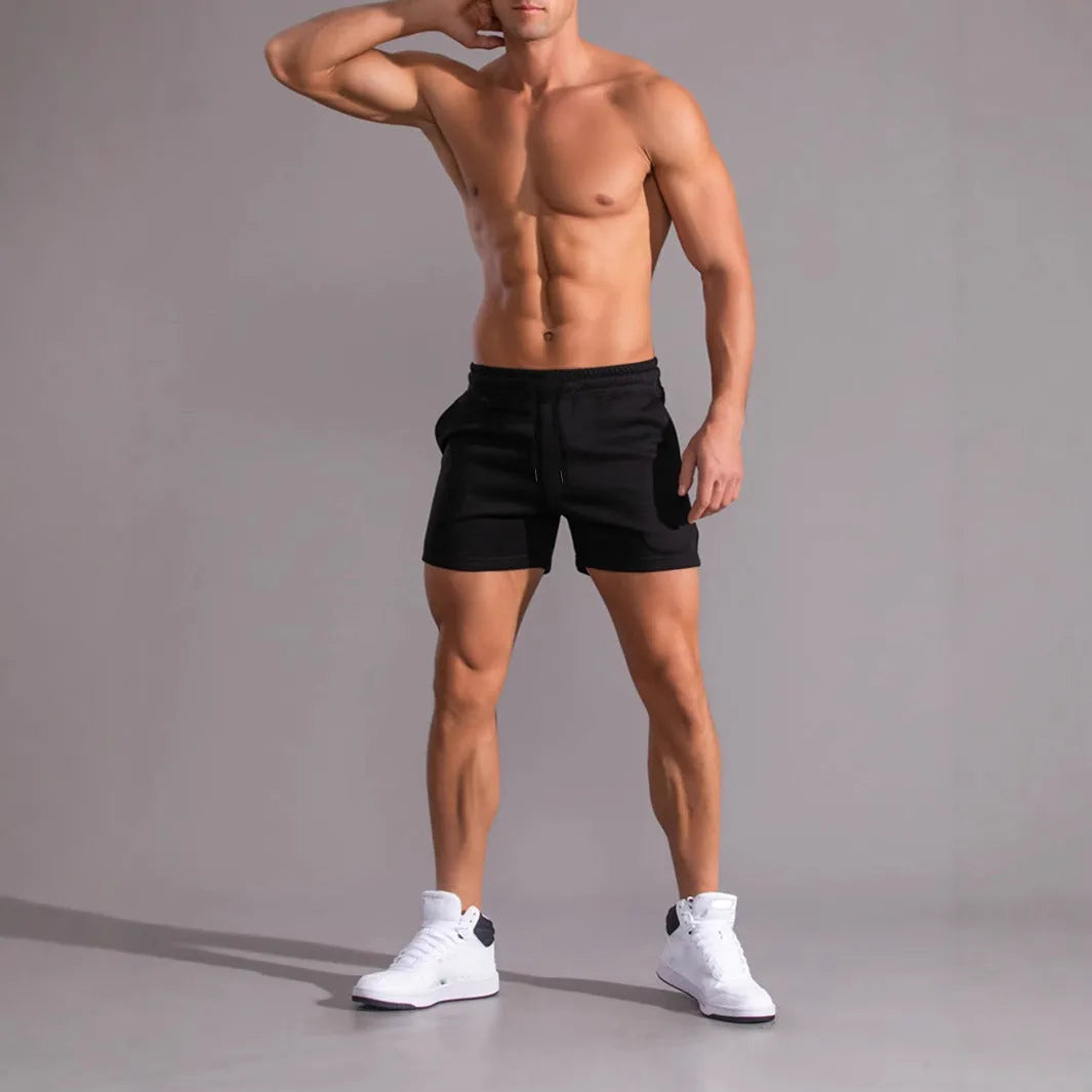 Set of three solid colour men's drawstring shorts in black, khaki, and light brown laid flat.