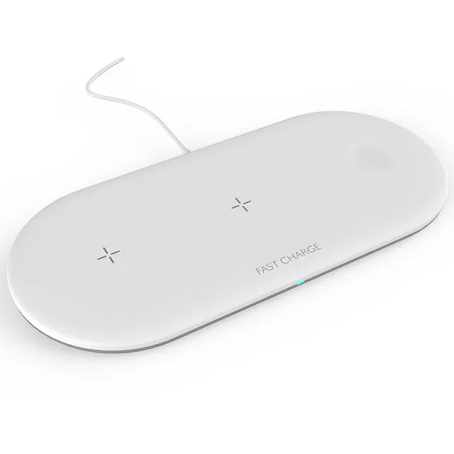 White three-in-one wireless charging stand holding an iPhone, Apple Watch, and AirPods on a wooden desk.