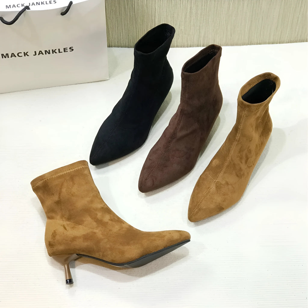 Black pointed toe ankle boots with a stiletto heel on a plain background.