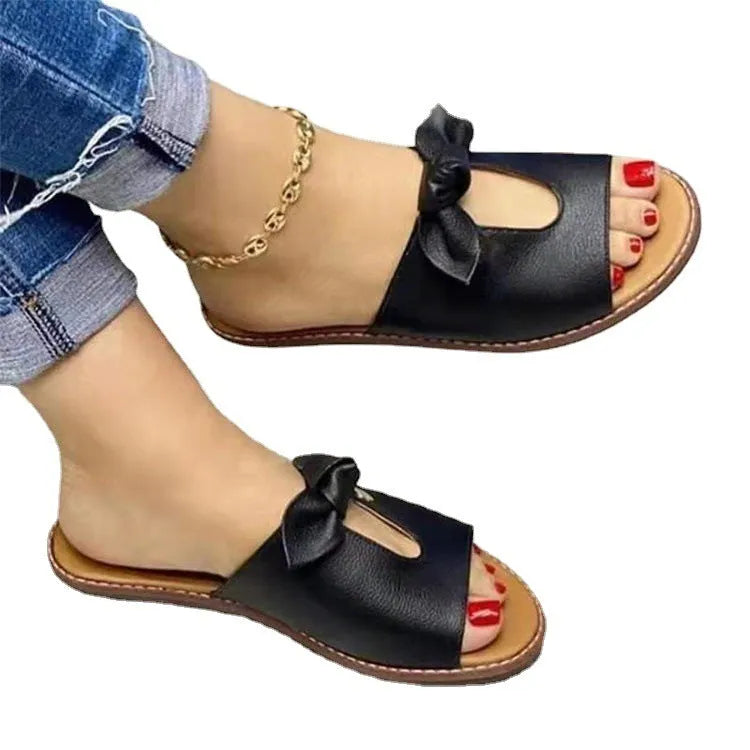 Women's black fish-mouth slippers with a bow detail on the upper, showing a rubber sole.