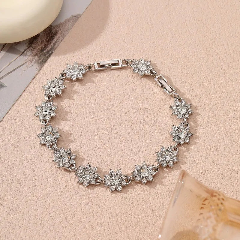 Electroplated zinc alloy bracelet with flower-shaped coloured gems in gold or silver tone.