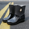 Women's purple PVC middle tube rain boots with a non-slip sole on a wet surface.