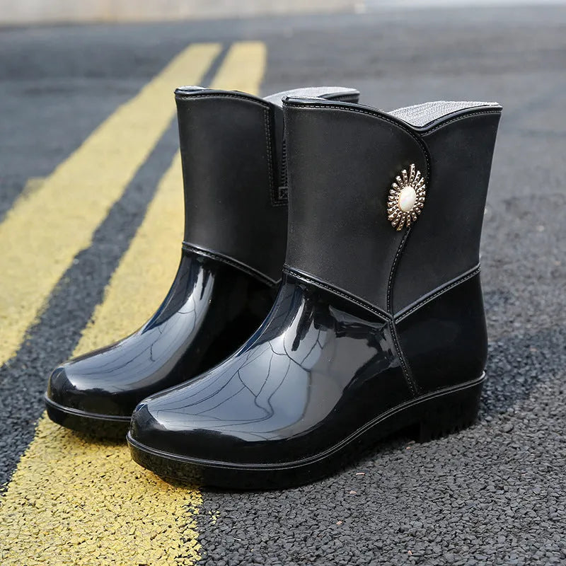 Women's purple PVC middle tube rain boots with a non-slip sole on a wet surface.