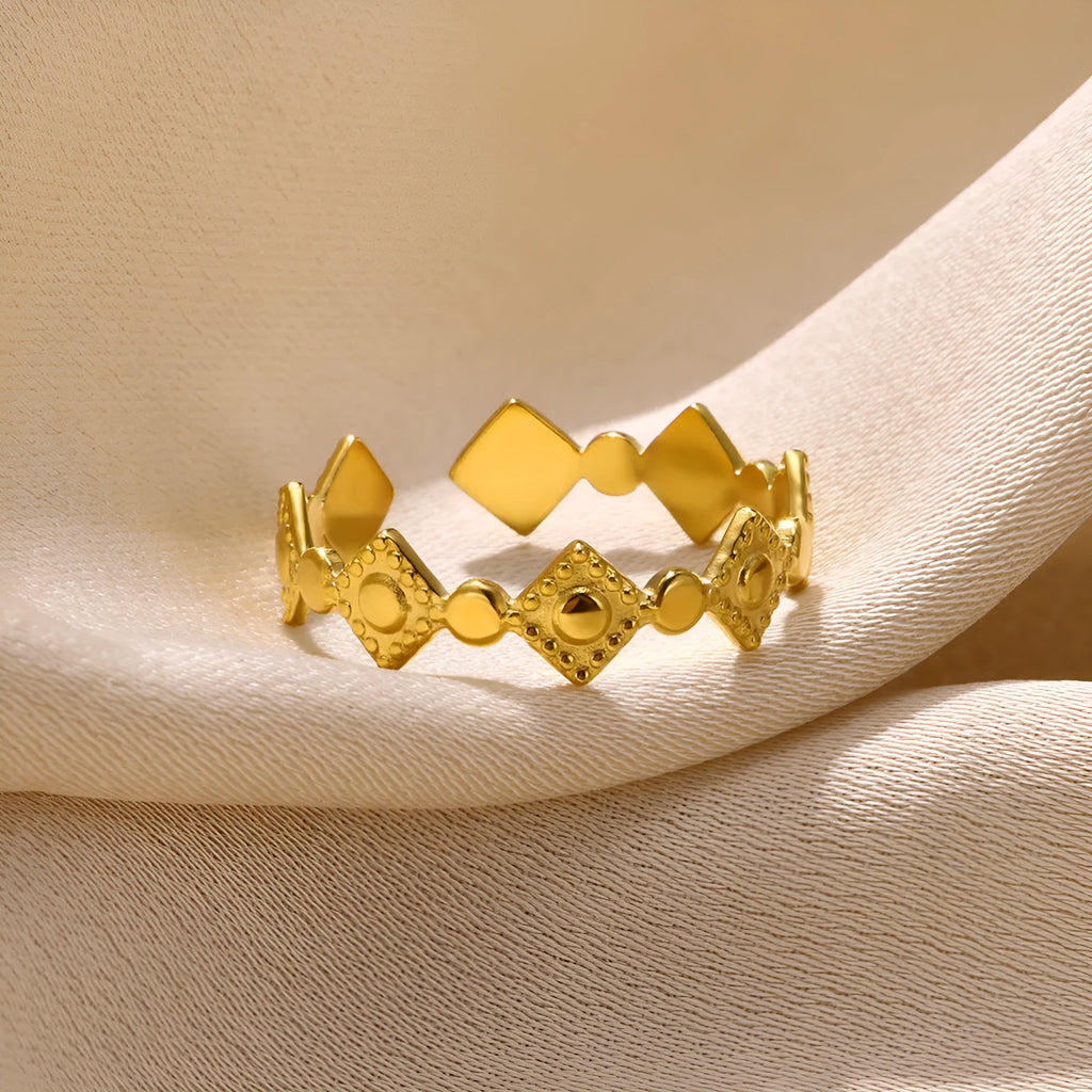 Gold diamond coloured geometric titanium steel ring for women on a flat surface.