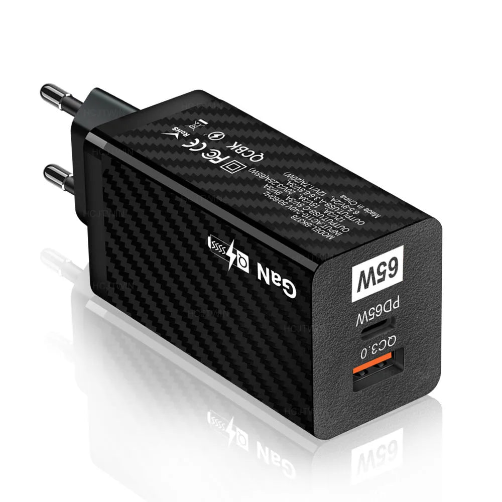 Compact white GaN 65W USB-C laptop charger with EU, UK, and US plug attachments on a table.