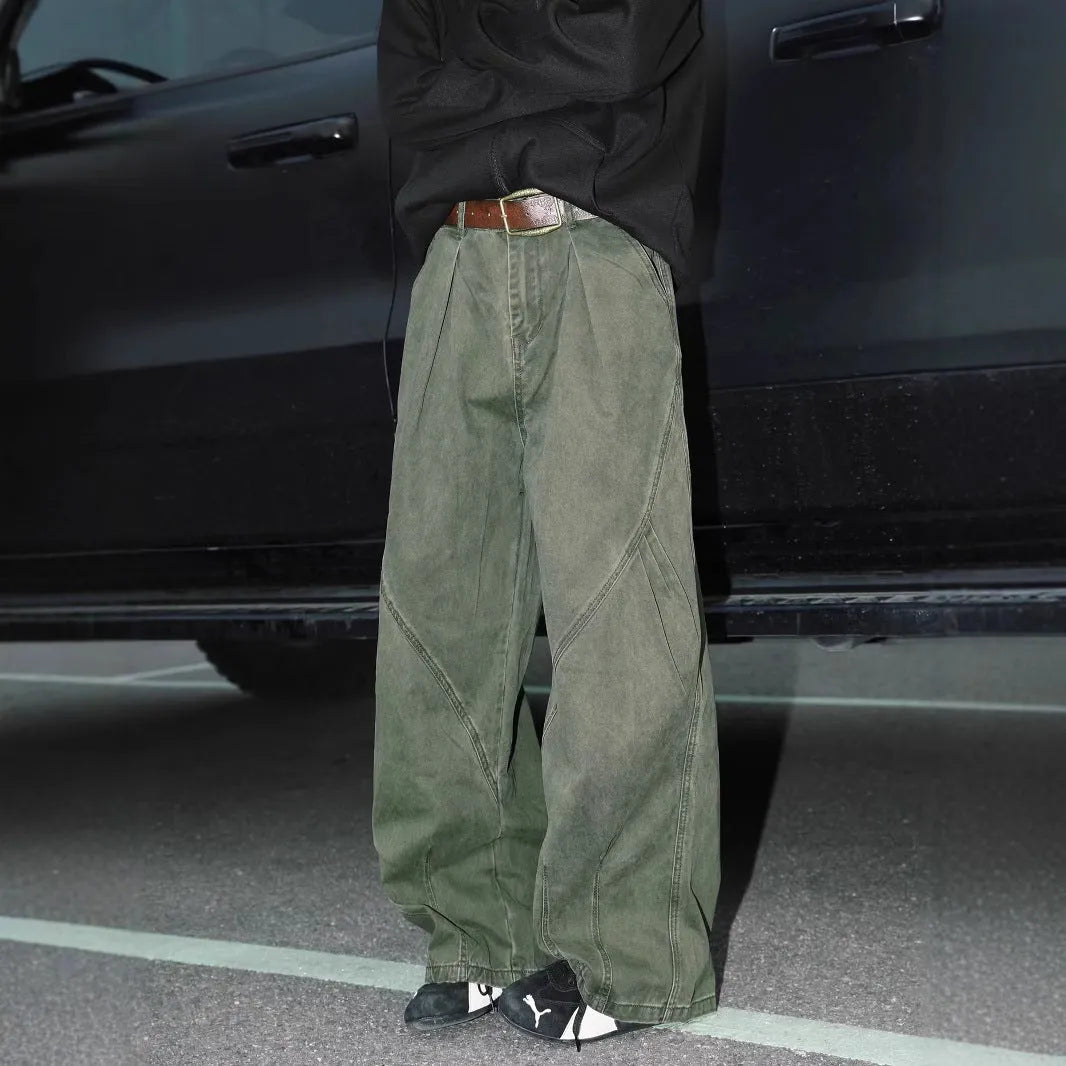 Man wearing straight-leg pleated trousers in a cotton-polyester blend, available in black, brown, and apricot.
