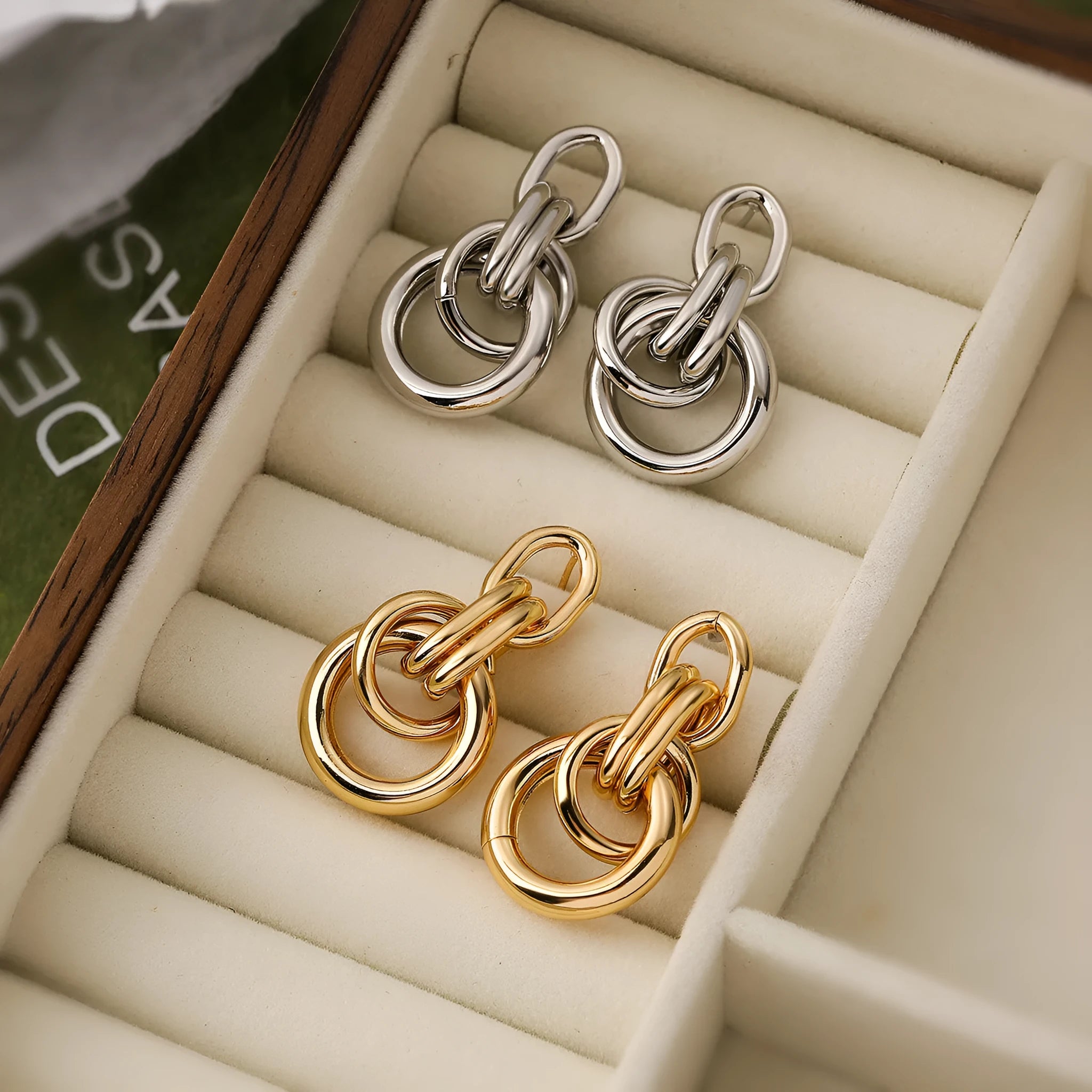A pair of gold-colour geometric earrings with an irregular, high-profile design on a white background.