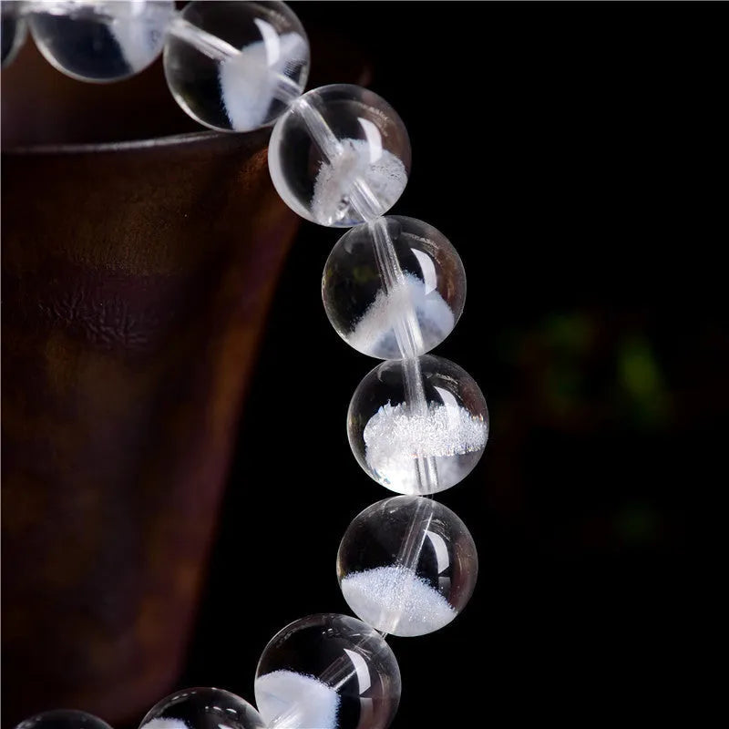 Women's white crystal pyramid bead bracelet with a Ruyi charm on a wrist.