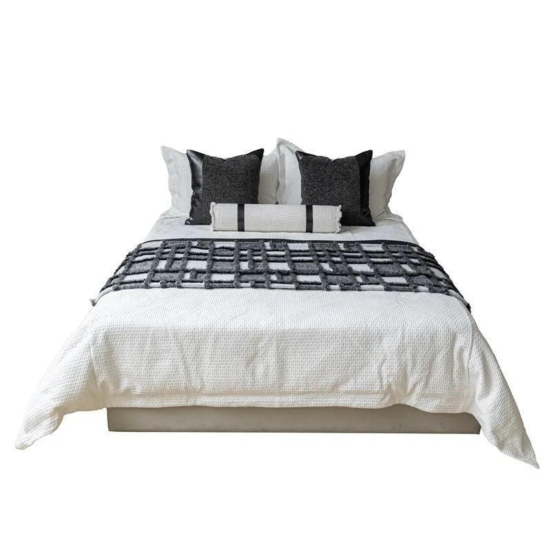 Modern grey and white plaid bed runner blanket set with a pillowcase and leather round pillow on a 1.5m bed.