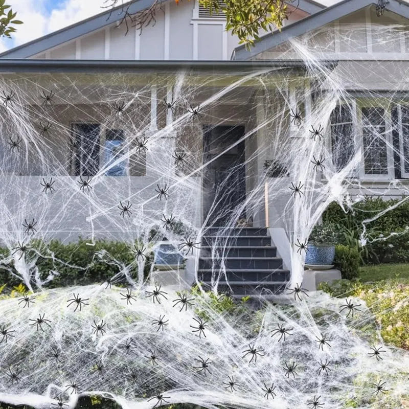 White cotton spider web Halloween decoration with integrated synthetic spiders draped over fence