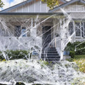 White cotton spider web Halloween decoration with integrated synthetic spiders draped over fence