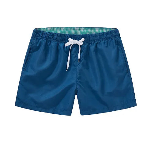 Men's straight-leg polyester beach shorts on a hanger, showing the classic fit and available in multiple solid colours.