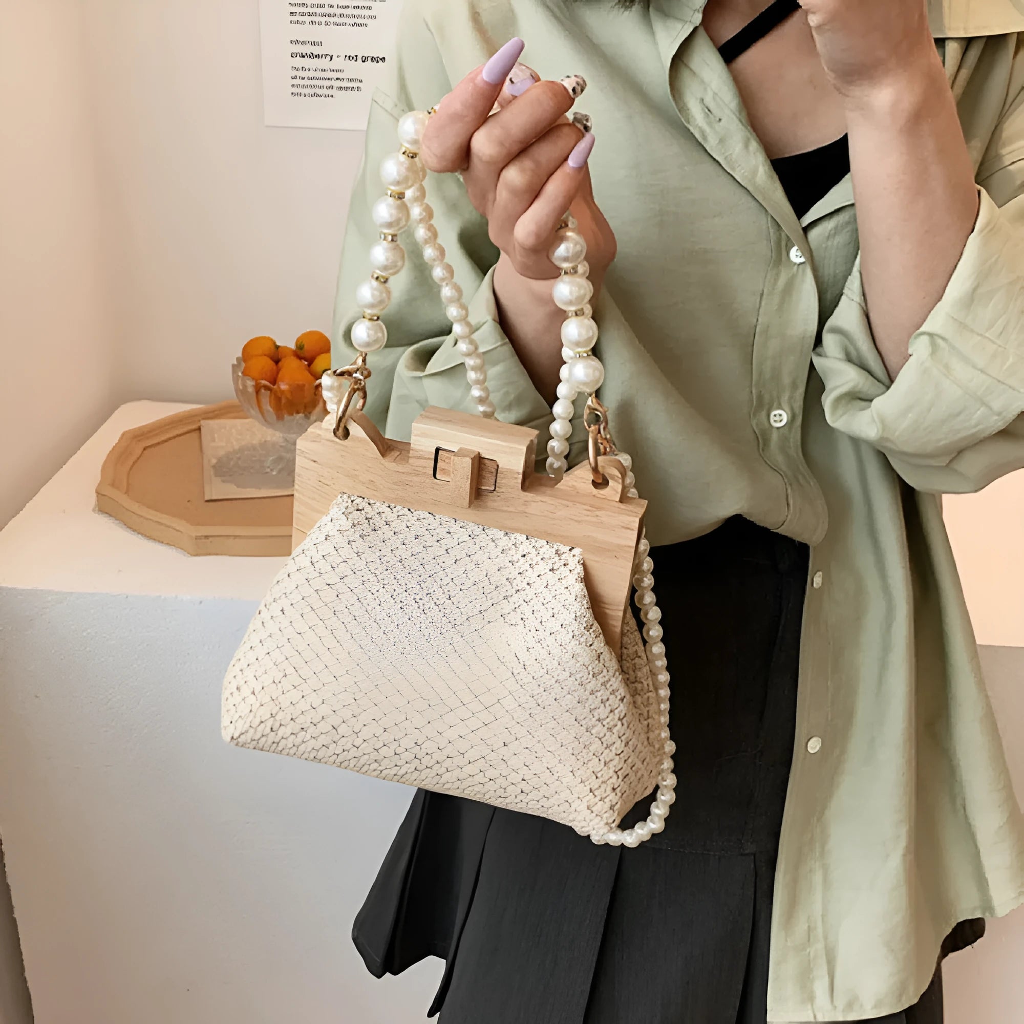 Women's woven straw shoulder bag with pearl chain strap and zippered interior pockets in beige, black, or khaki