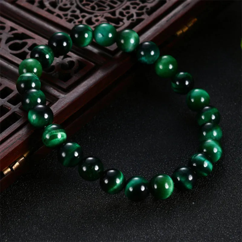 Polished green tiger eye stone beaded bracelet on a white background, showing geometric shaped beads.