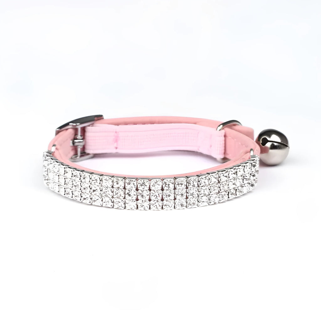 Close-up of a soft red velvet cat collar with a line of sparkling rhinestones and an adjustable buckle.