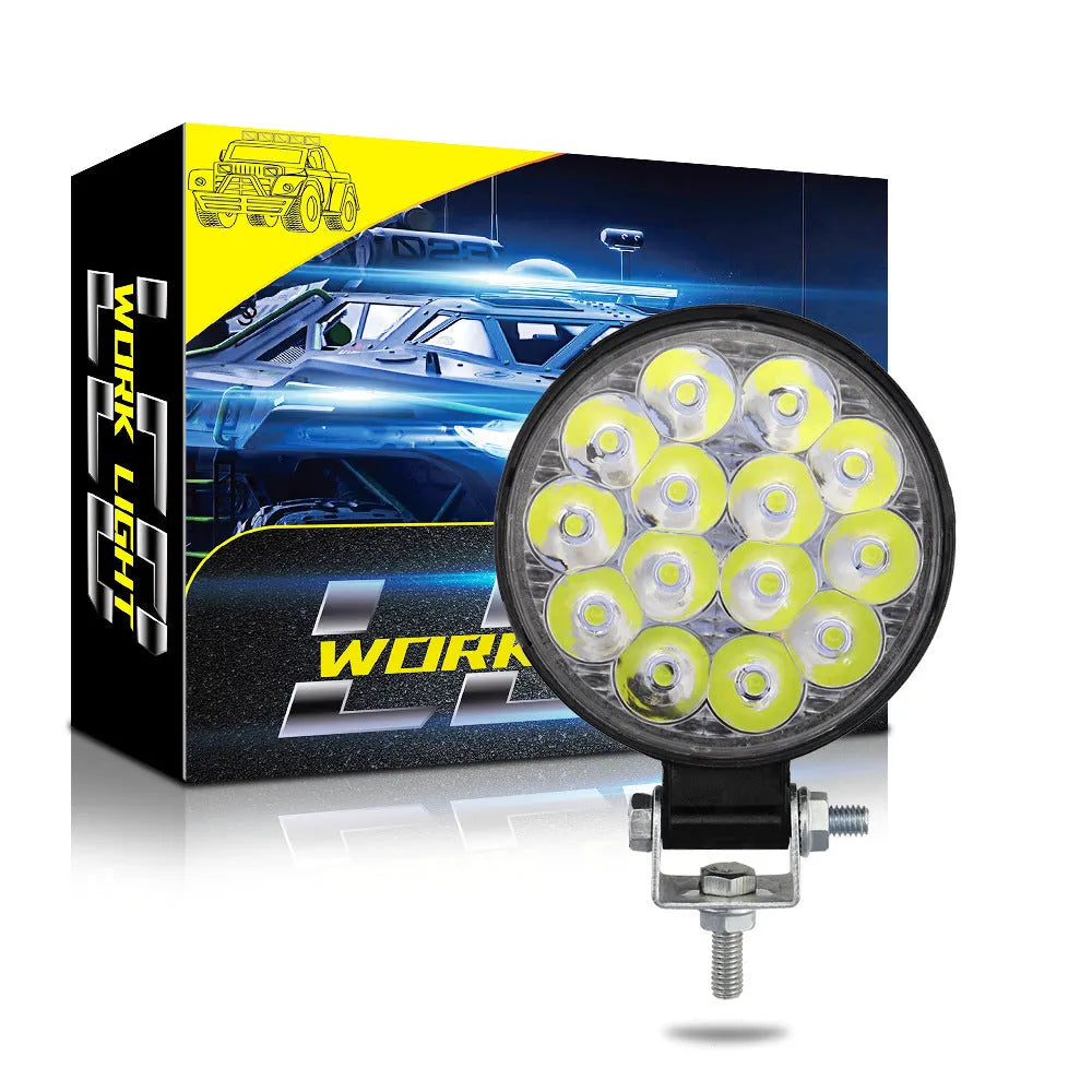 White mini round LED work light with aluminium housing, mounted as an auxiliary car or truck light.