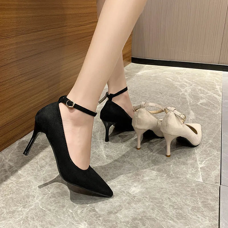 Black and creamy white women's stiletto heel pumps with a metal buckle detail on the upper.