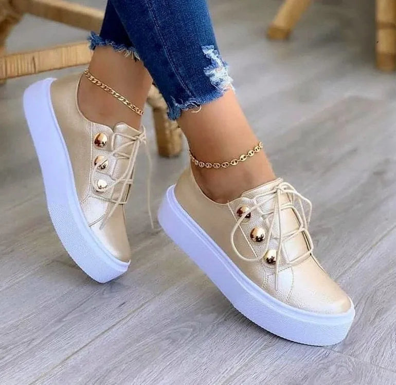 Women's white lace-up flats sneakers with round toe and silver rivet details on the side.