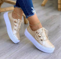 Women's white lace-up flats sneakers with round toe and silver rivet details on the side.