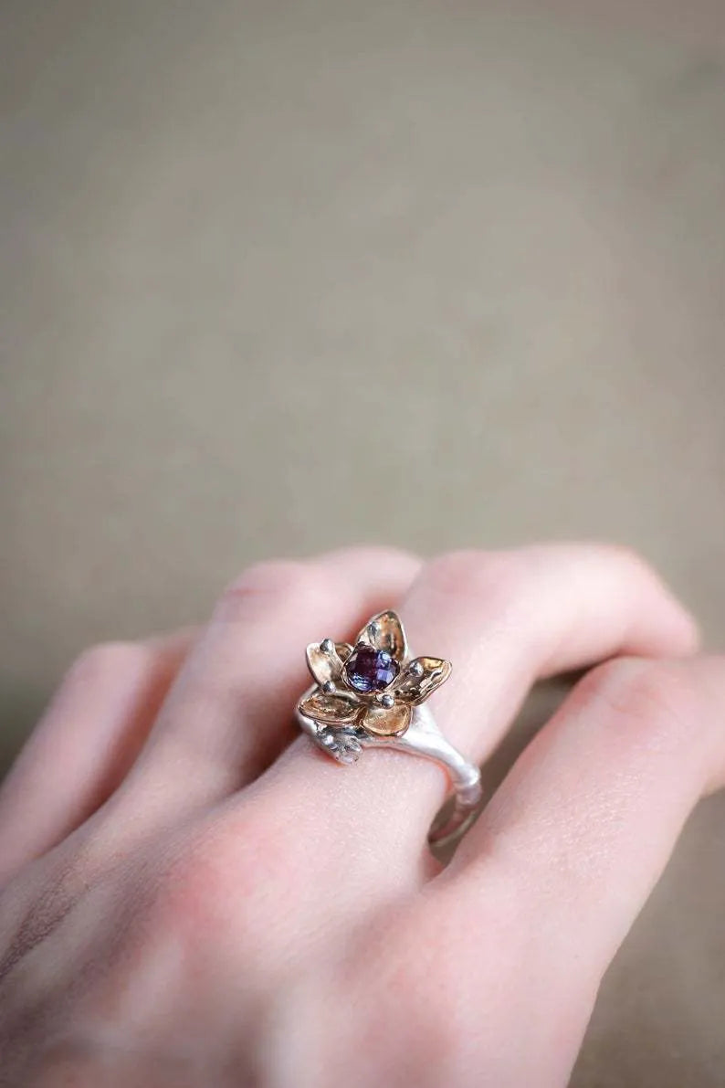 Silver two-tone alloy ring with geometric floral design on a white background.