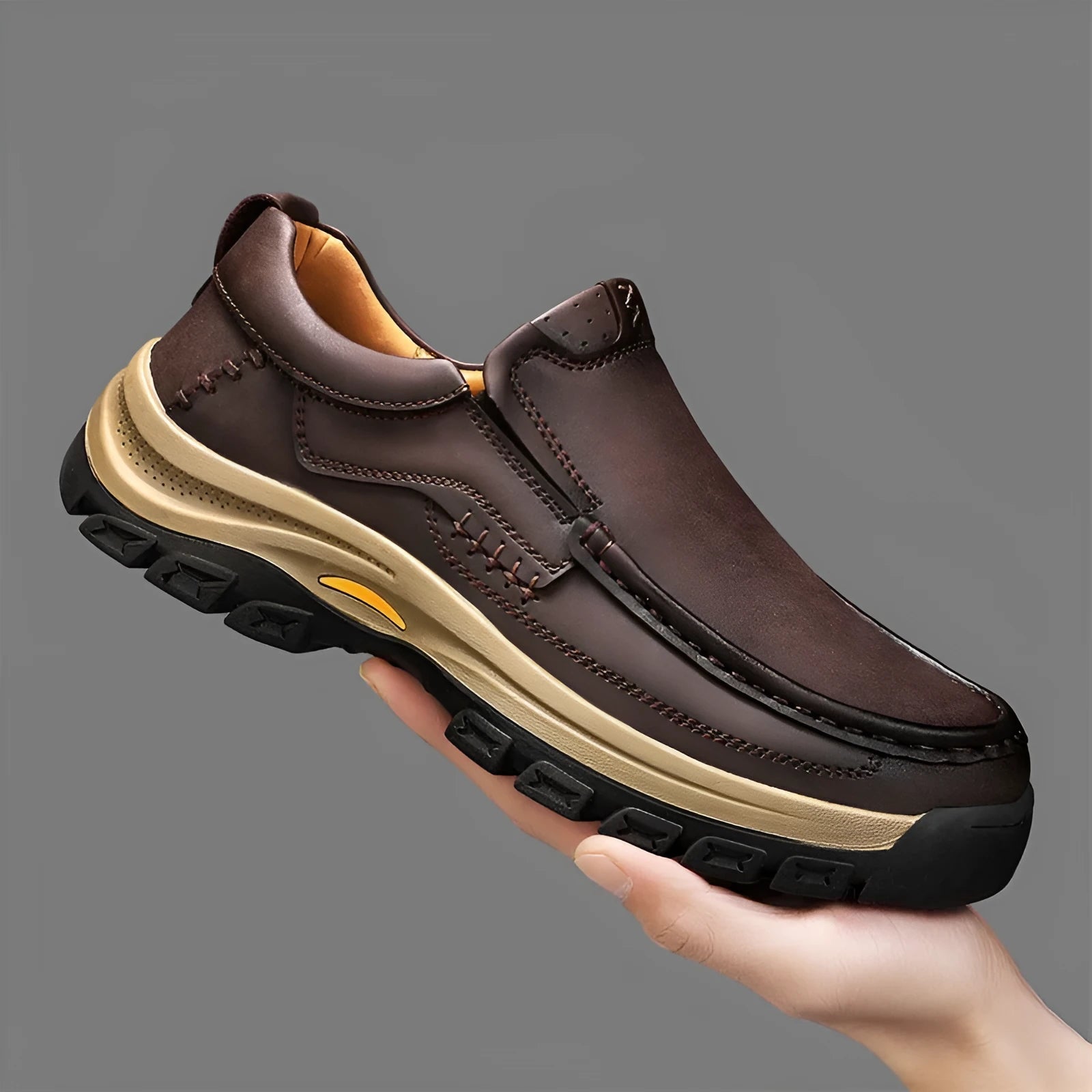 Men's black leather mountaineering shoes with thick rubber soles and round toe on a rocky path.