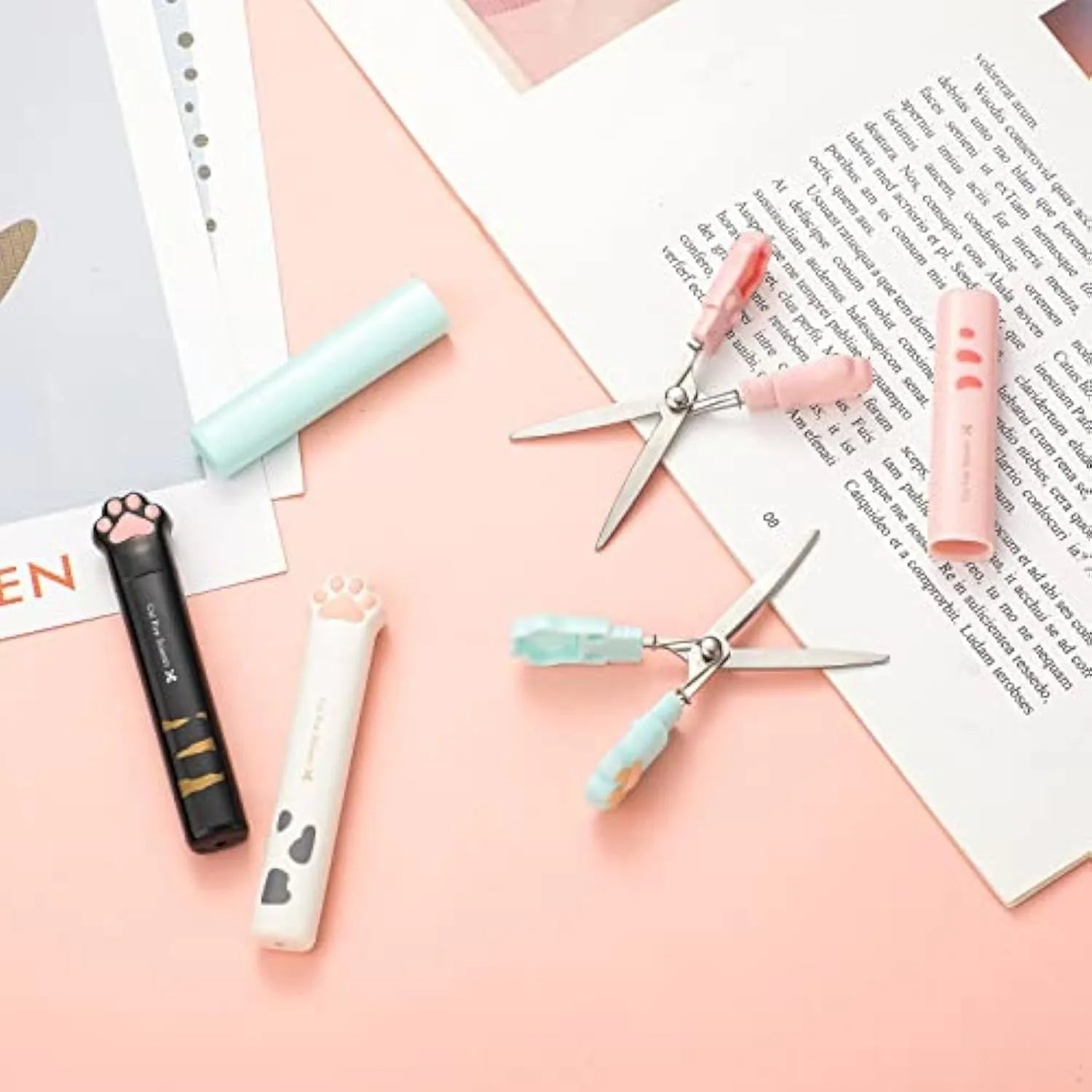 Set of four small folding scissors with cat paw handles in black, blue, pink, and white colours.
