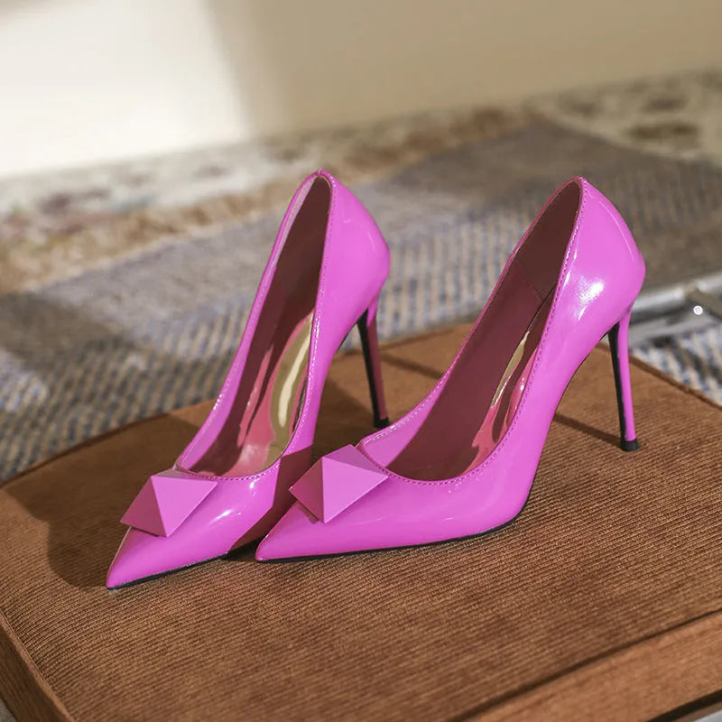 Pink women's pointed toe stiletto high heels with a rivet buckle on the ankle strap.