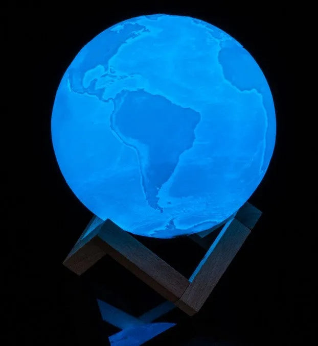 3D printed moon lamp glowing on a wooden stand with touch ring at base