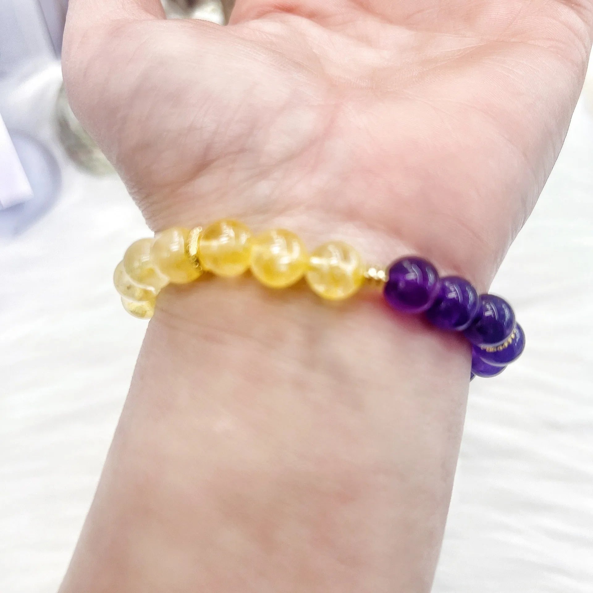 Handmade women's yellow and purple amethyst crystal bracelet showing manual craftsmanship details