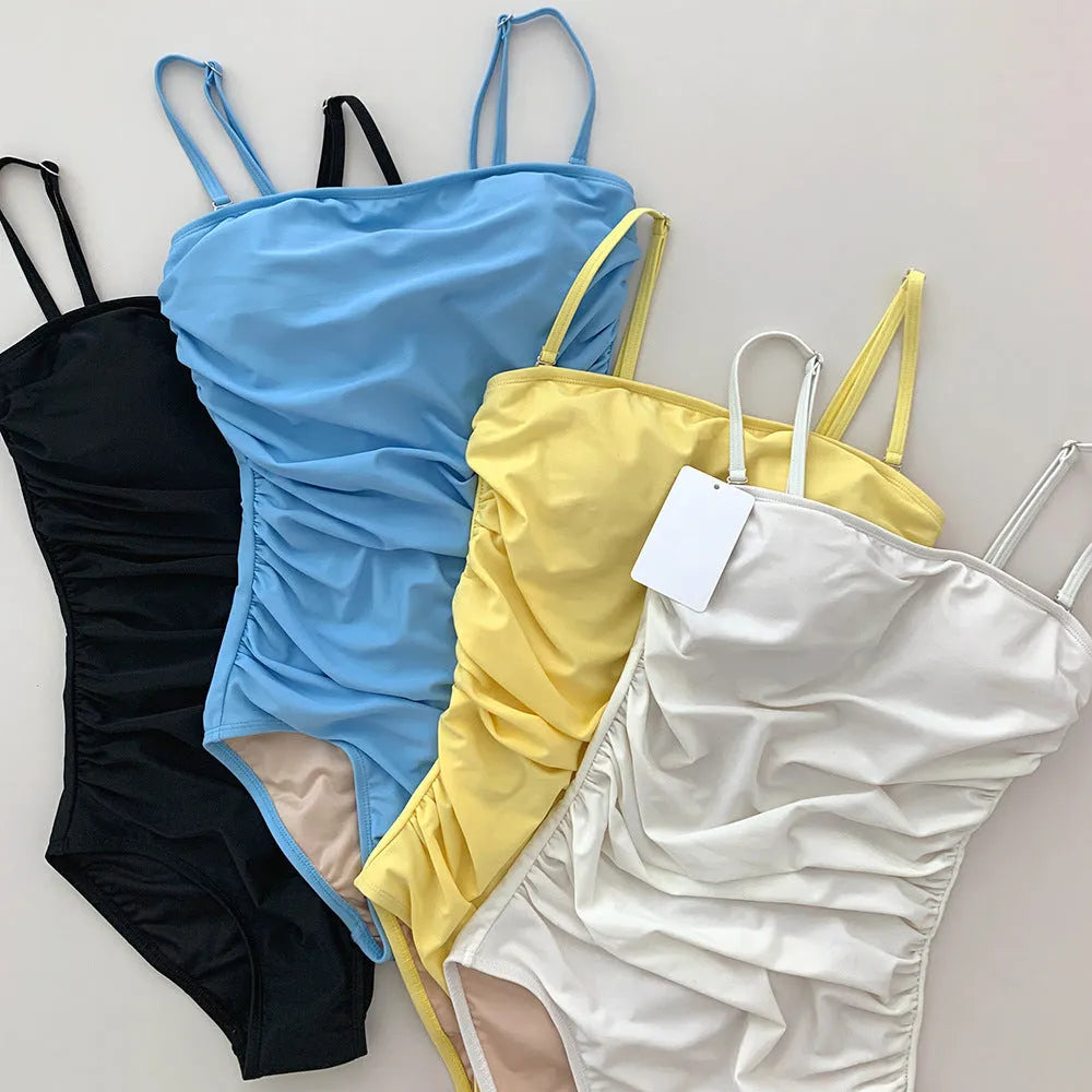 Women's blue sling style one-piece swimsuit with a belted pleated waist detail on a model.